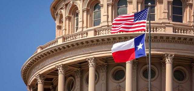 American and Texas state flags flying on the dome of the Texas State Capitol building in Austin